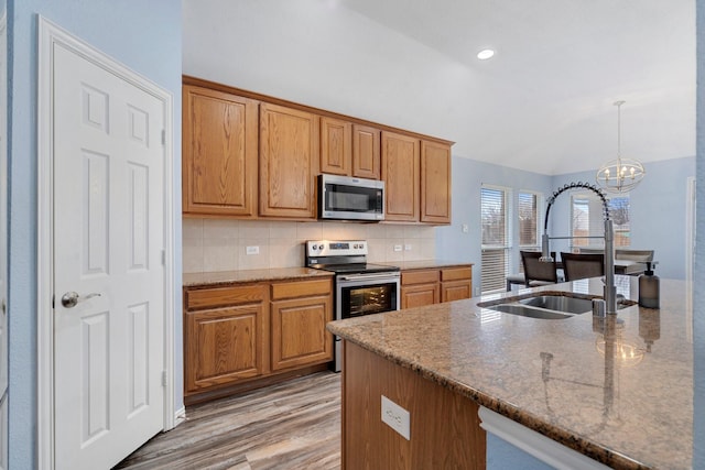 kitchen featuring stainless steel appliances, a notable chandelier, backsplash, dark stone countertops, and decorative light fixtures