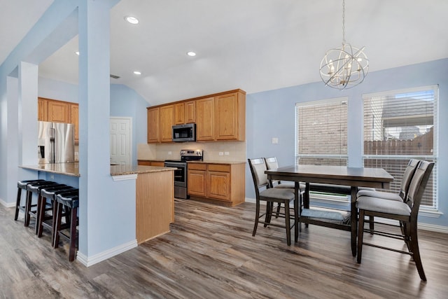 kitchen with wood-type flooring, decorative light fixtures, a chandelier, lofted ceiling, and appliances with stainless steel finishes