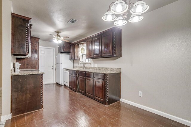 kitchen with dark brown cabinetry, sink, ceiling fan with notable chandelier, and white appliances