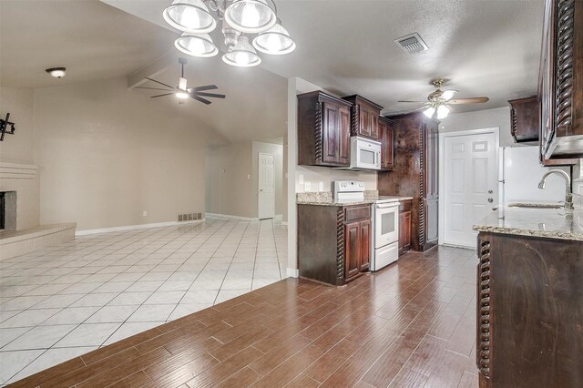 kitchen featuring dark brown cabinetry, light stone counters, sink, and white appliances