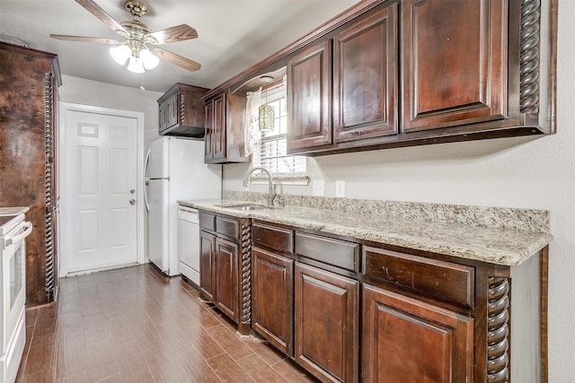 kitchen featuring light stone counters, dark brown cabinets, white dishwasher, ceiling fan, and sink