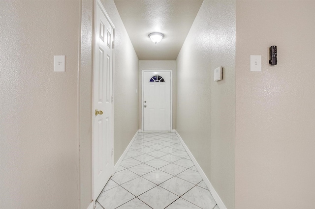 hall featuring light tile patterned floors and a textured ceiling