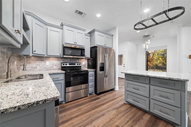 kitchen with backsplash, light stone counters, sink, and appliances with stainless steel finishes