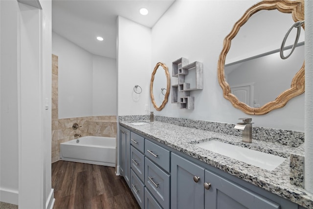 bathroom featuring vanity, hardwood / wood-style floors, a bathtub, and tile walls