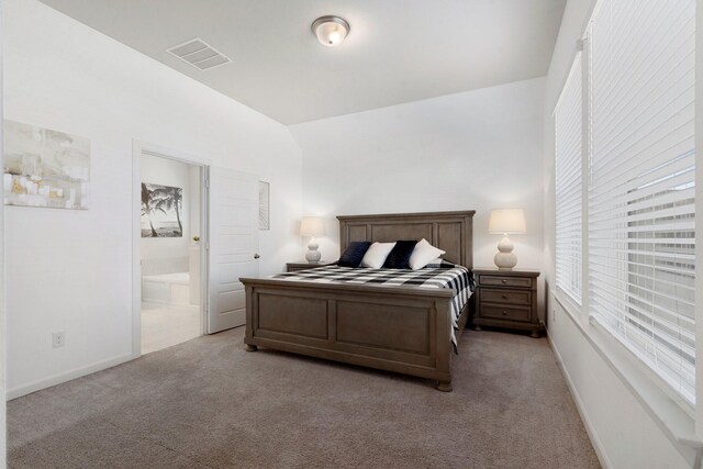 bedroom with light carpet and ensuite bathroom