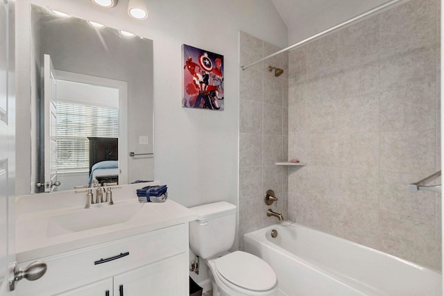 full bathroom featuring toilet, vanity, lofted ceiling, and tiled shower / bath