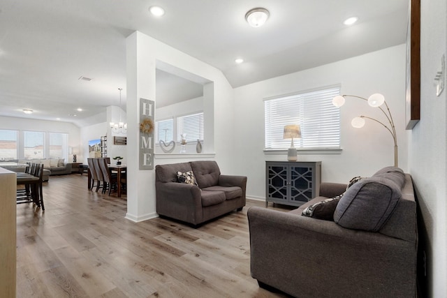 living room featuring a chandelier, light hardwood / wood-style flooring, and lofted ceiling