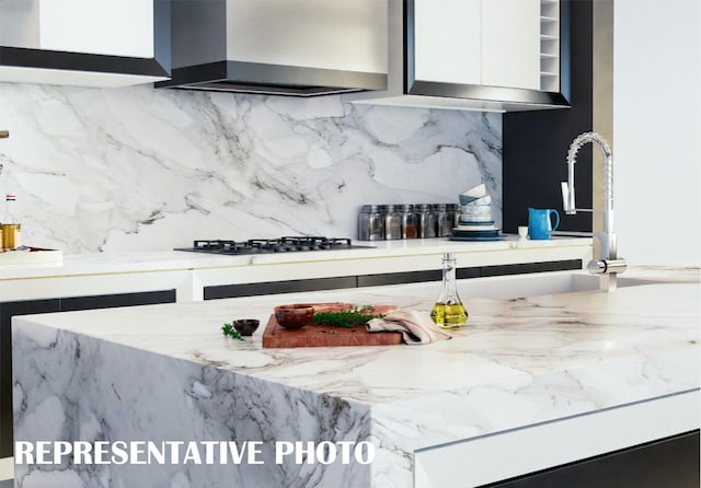 kitchen featuring gas cooktop, tasteful backsplash, and wall chimney range hood