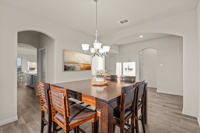 dining space featuring light wood-type flooring and a chandelier