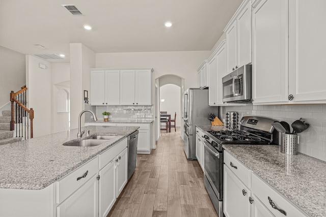 kitchen featuring backsplash, sink, light wood-type flooring, white cabinetry, and stainless steel appliances