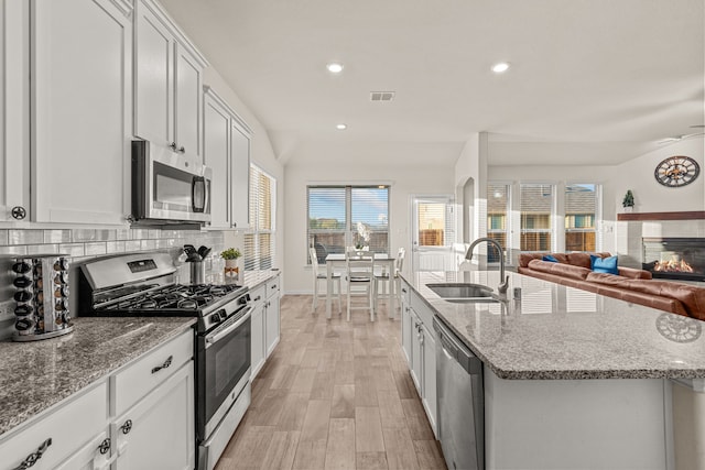 kitchen featuring light hardwood / wood-style floors, white cabinetry, stainless steel appliances, and an island with sink