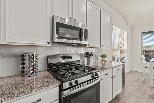 kitchen with light stone countertops, appliances with stainless steel finishes, backsplash, and white cabinetry