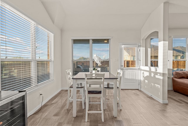 dining room with light hardwood / wood-style flooring, vaulted ceiling, and a wealth of natural light