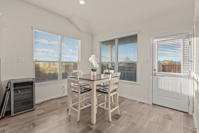 dining room with wine cooler, light hardwood / wood-style floors, a wealth of natural light, and vaulted ceiling