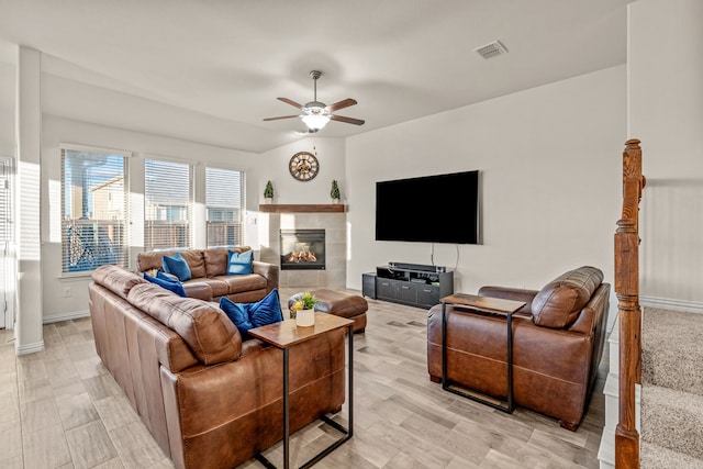 living room featuring ceiling fan and a tile fireplace