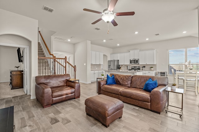 living room featuring ceiling fan, sink, and light hardwood / wood-style floors