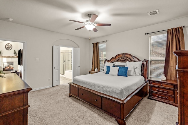 carpeted bedroom with multiple windows, connected bathroom, and ceiling fan