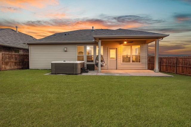 back house at dusk featuring a lawn, a patio area, central AC unit, and a hot tub