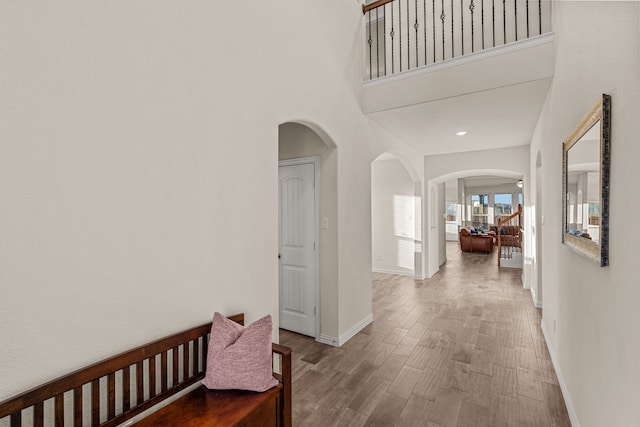 corridor featuring a towering ceiling and hardwood / wood-style flooring