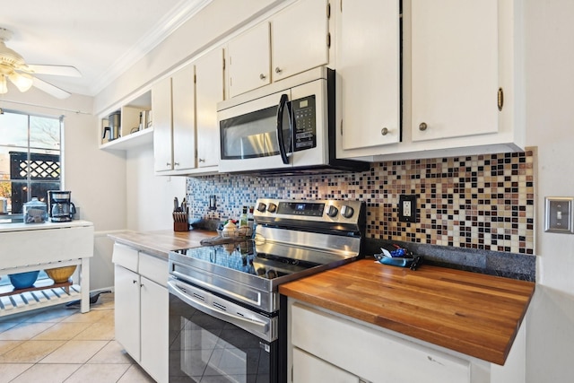 kitchen featuring white cabinetry, stainless steel appliances, backsplash, light tile patterned floors, and ornamental molding