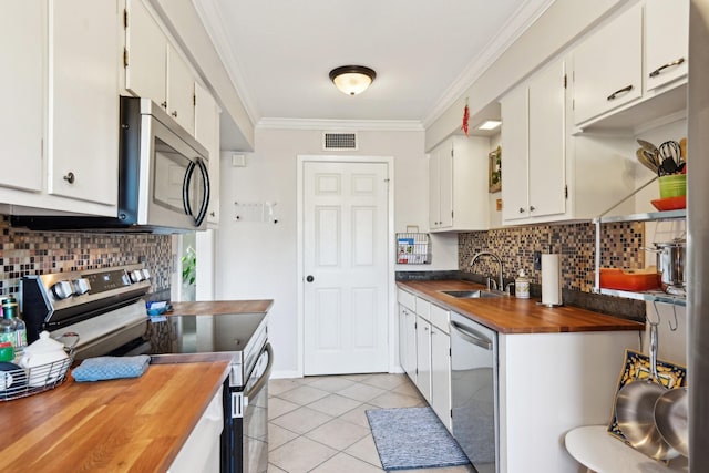 kitchen featuring ornamental molding, stainless steel appliances, sink, white cabinetry, and light tile patterned flooring