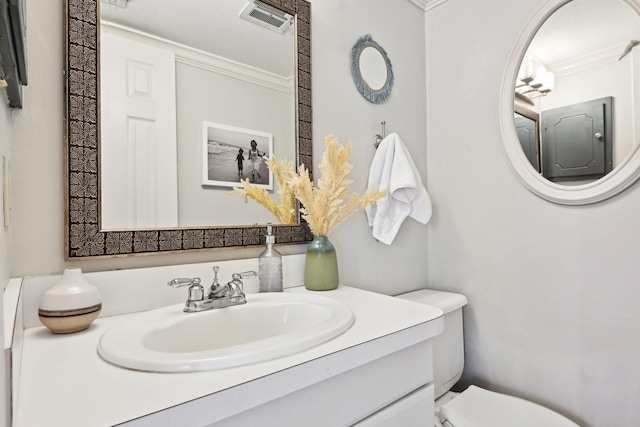 bathroom featuring toilet, vanity, and ornamental molding