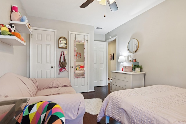 bedroom with dark hardwood / wood-style floors, two closets, and ceiling fan