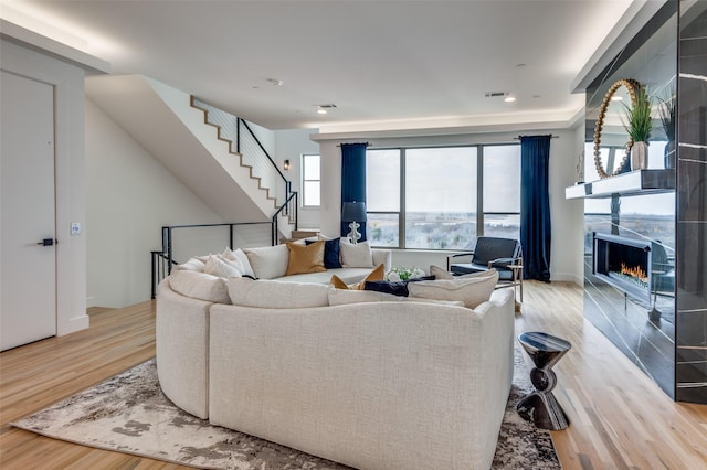 living room featuring a tile fireplace and light hardwood / wood-style floors