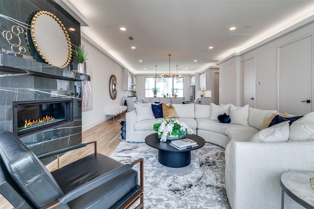 living room with a fireplace, light hardwood / wood-style flooring, and a chandelier