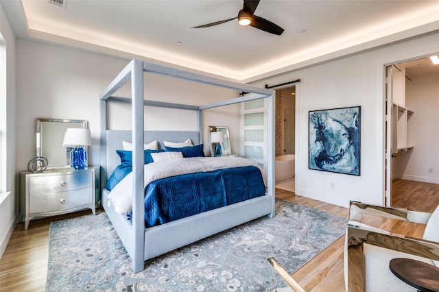 bedroom featuring connected bathroom, ceiling fan, and light hardwood / wood-style flooring