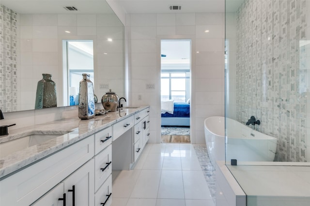 bathroom featuring tile patterned floors, a bathing tub, vanity, and tile walls