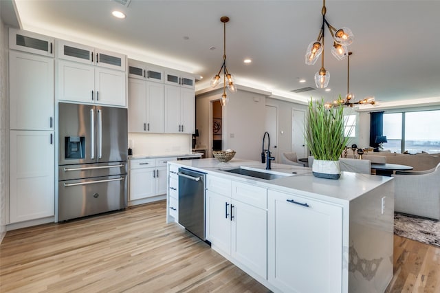 kitchen with a kitchen island with sink, white cabinetry, sink, and stainless steel appliances