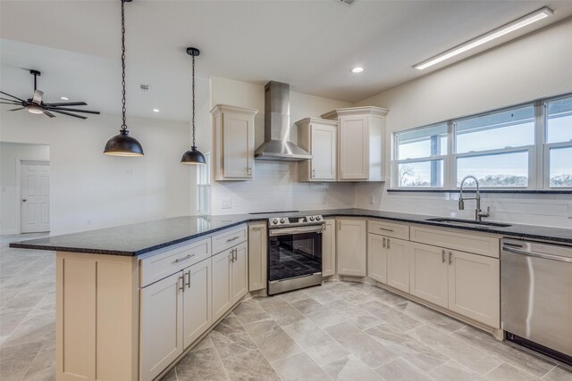 kitchen with tasteful backsplash, stainless steel appliances, sink, wall chimney range hood, and pendant lighting