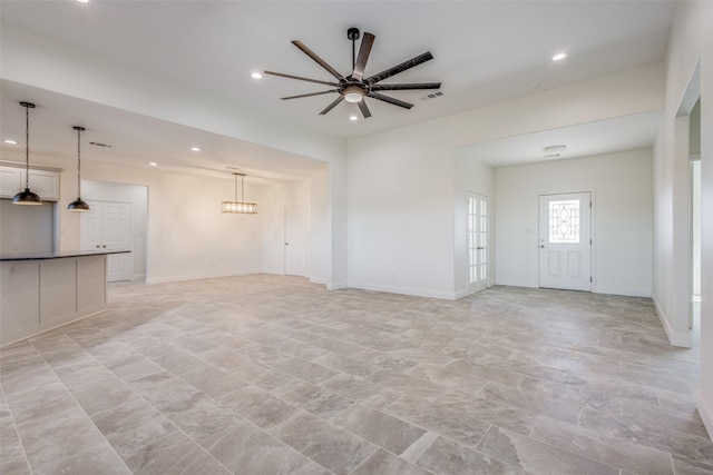 unfurnished living room with ceiling fan with notable chandelier