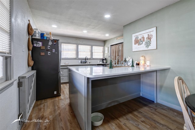 kitchen featuring stainless steel refrigerator, kitchen peninsula, dark hardwood / wood-style flooring, and sink