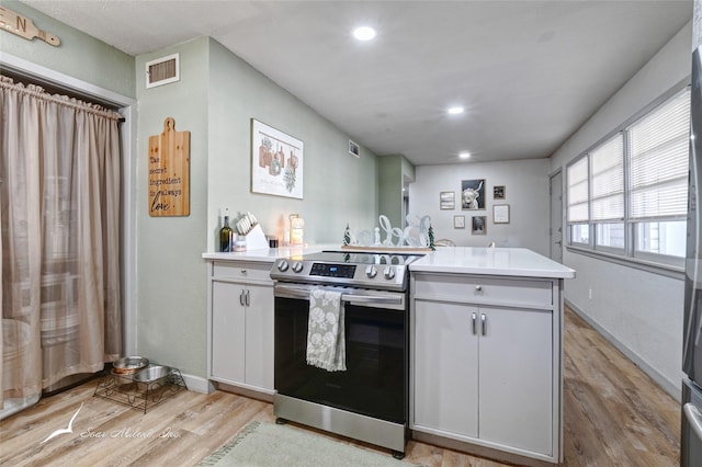 kitchen featuring white cabinets, stainless steel electric range, and light wood-type flooring