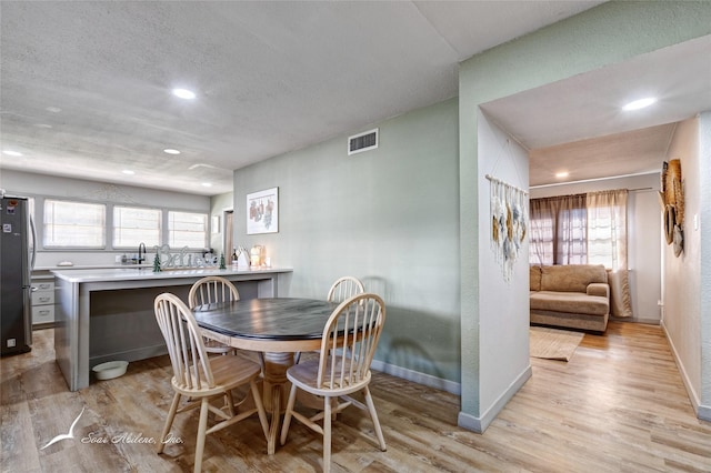 dining space with sink and light hardwood / wood-style floors