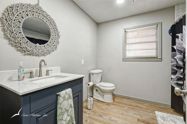 bathroom with wood-type flooring, vanity, and toilet