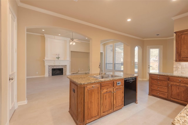 kitchen with a large fireplace, a sink, black dishwasher, brown cabinetry, and a center island with sink