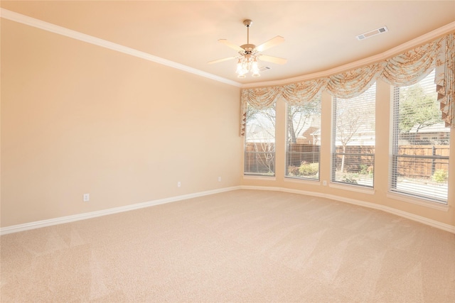 empty room featuring light colored carpet, crown molding, visible vents, and baseboards