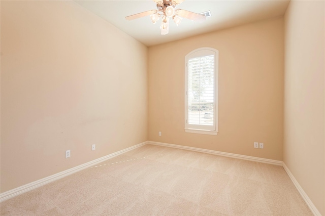 empty room with baseboards, visible vents, a ceiling fan, and light colored carpet