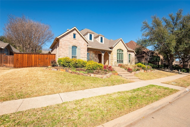 view of front facade featuring stone siding, fence, and a front lawn