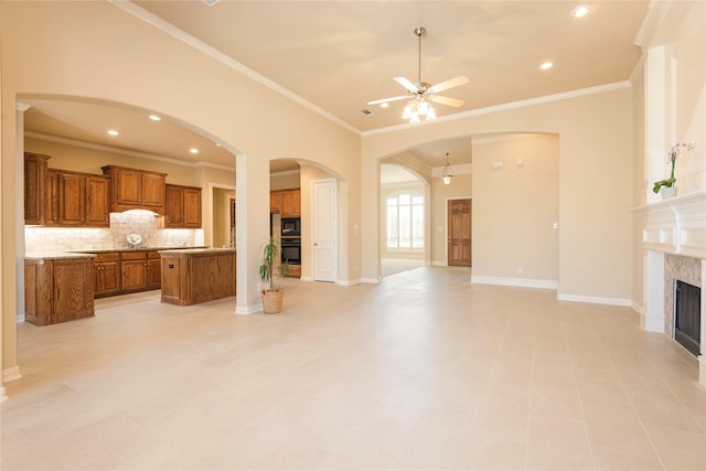 unfurnished living room featuring a premium fireplace, baseboards, crown molding, and recessed lighting