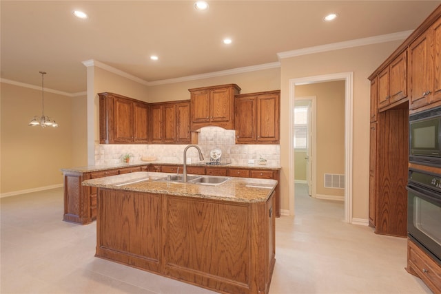 kitchen featuring light stone counters, visible vents, brown cabinetry, a sink, and black appliances