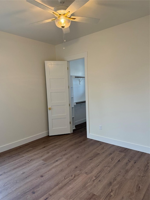 unfurnished room featuring dark wood-style floors, a ceiling fan, and baseboards