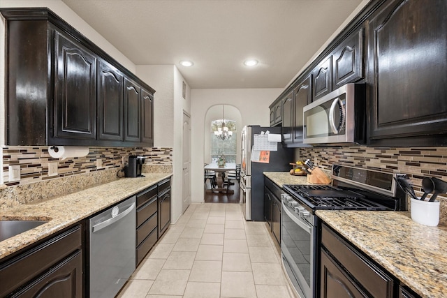 kitchen featuring light stone counters, light tile patterned floors, backsplash, and appliances with stainless steel finishes