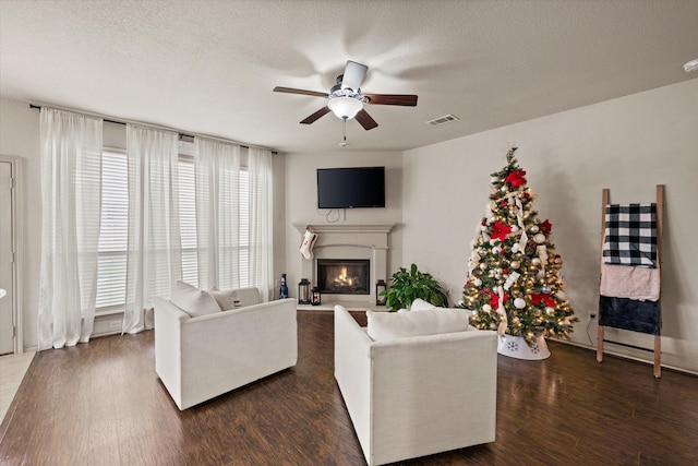 living room with dark hardwood / wood-style flooring, ceiling fan, and a textured ceiling