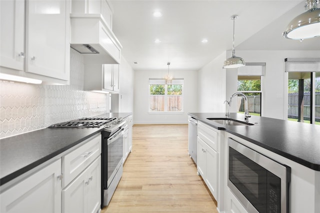 kitchen with premium range hood, sink, hanging light fixtures, white cabinetry, and stainless steel appliances