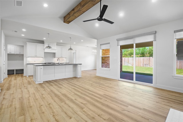 unfurnished living room with vaulted ceiling with beams, ceiling fan, light wood-type flooring, and sink