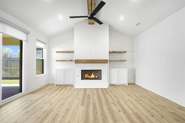 unfurnished living room with a tile fireplace, lofted ceiling, ceiling fan, and light hardwood / wood-style flooring